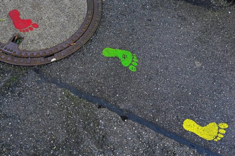 Colourful footprints on manhole covers and asphalt