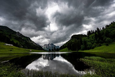Groeppelensee with reflection of the Altmann summit in the background under a threatening cloudy sky
