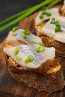 Closeup view of sandwich with salty herring and spring onion