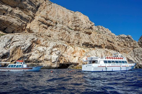 Excursion boats in front of rocky coast of Capo Caccia with Grotta Nereo cave
