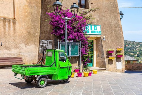 Green Piaggio Ape utility vehicle in front of the cathedral of Rio nell Elba