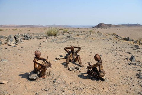 Three stone men by the artist RENN at a fireplace