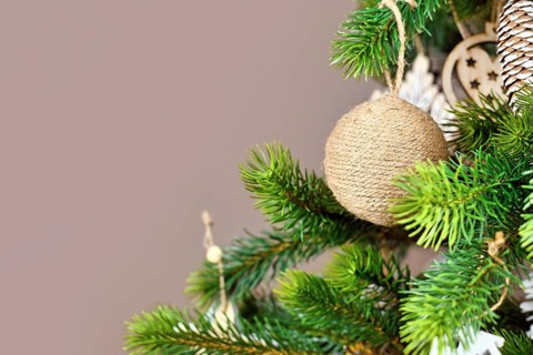 Christmas tree branches with natural ornament bauble made from beige jute robe with copy space