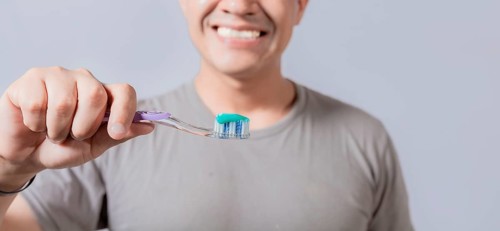 Young man showing toothbrush with toothpaste isolated