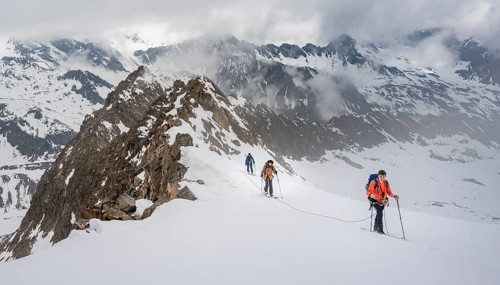 Ski tourers walking on the rope on the glacier in winter in the mountains