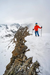 Ski tourers on rocky ridge with snow