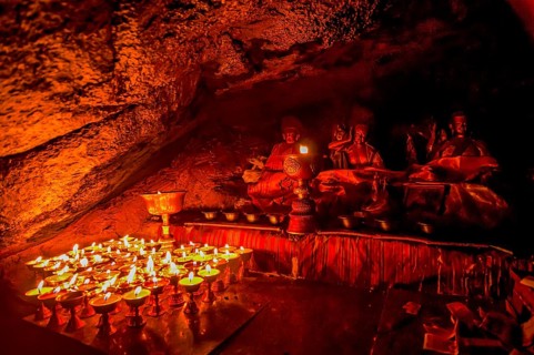 Cave with candles and Buddha images along the Kailash Kora