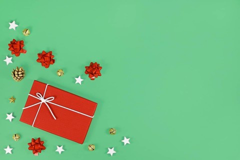 Red Christmas gift box surrounded by golden seasonal pine cones