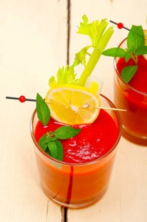 Fresh tomato juice gazpacho soup on a glass over white wood table