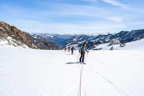 Ski tourers walking on the rope on the glacier