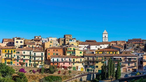 The mountain village of Capoliveri with pastel-coloured house facades against a blue sky
