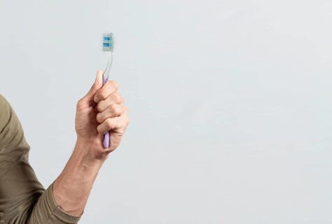 Hand holding toothbrush isolated on white. Male hand showing a toothbrush isolated. Toothbrush concept