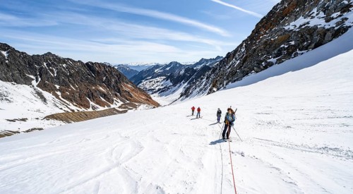 Group of ski tourers walking on the rope on the glacier
