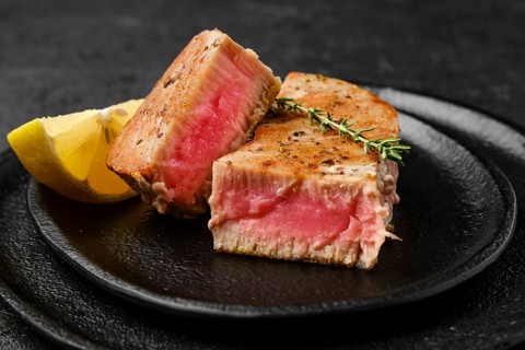 Closeup view of fried tuna steak on slate plate
