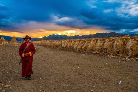 Monk walks along an eroded mud wall in the kingdom of Guge