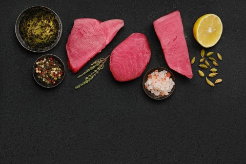 Top view of raw fresh tuna steak and spices on black background