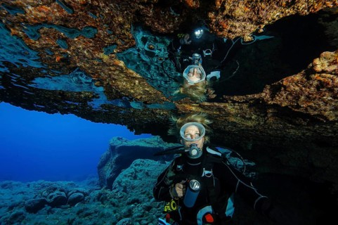 Diver sees reflection underwater in air bubble in cave ceiling in entrance of underwater cave