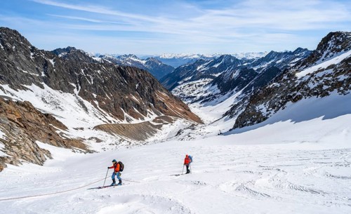 Two ski tourers walking on the rope on the glacier