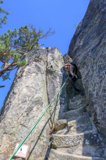 Woman descending steep stairs from the lookout point of the rock castle Vranov