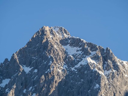 Blue sky above snowy alpine peak