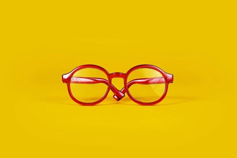 Small red round eye glasses on yellow background
