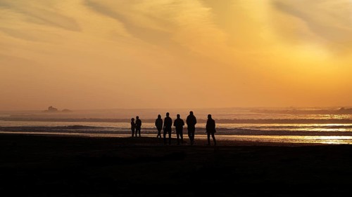 Group of tourists on the beach looking at the ruins of the watchtower Bordj El Berod on the horizon