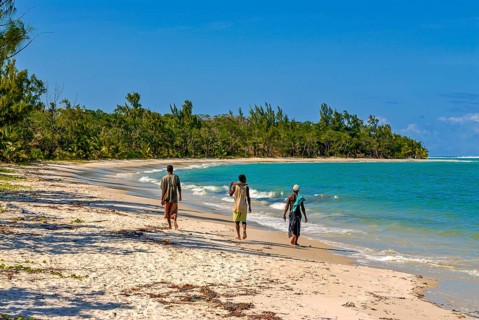 Workers walking on a long white sand beach in the east of the island Ile Sainte-Marie although Nosy Boraha