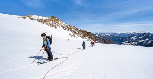Ski tourers walking on the rope on the glacier