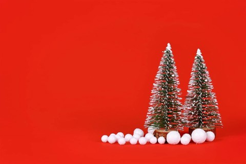Miniature Christmas trees and snowballs on red background with copy space