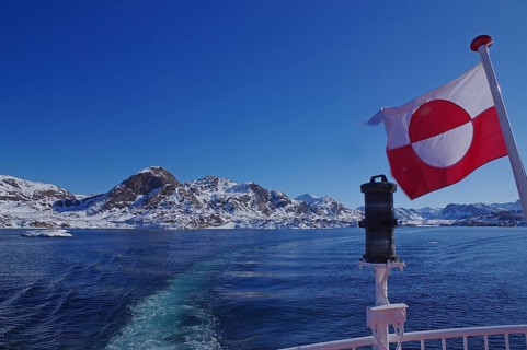Greenlandic flag waving in the wind at the end of a ship