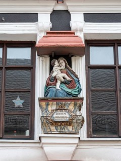 A sculpture of the Madonna and Jesus on the wall of a building in the town centre