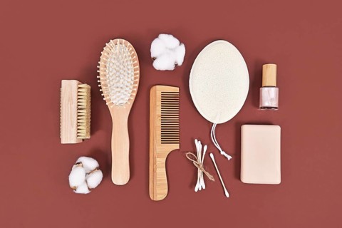 Eco friendly wooden beauty and hygiene products like comb and soap on brown background