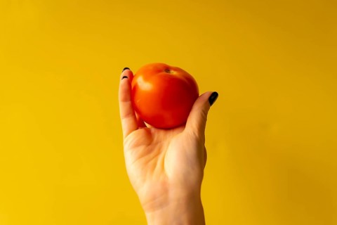 Woman's hand with a vegetable on a yellow background