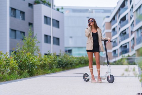 A businesswoman moving with an electric scooter around the city
