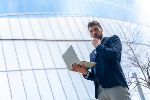 Young businessman looking with a computer in a glass building