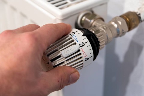 Man's hand turns thermostat