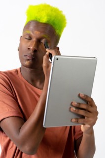 A gay black man putting on makeup