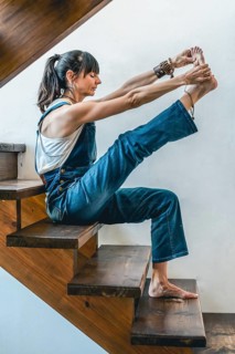 A woman doing stretching exercises on the stairs of her home. Wellbeing concept