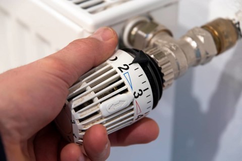 Man's hand turns thermostat