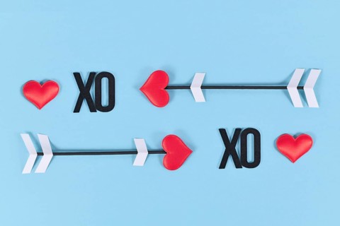 Valentine's day love arrow sand XO text letters on blue background