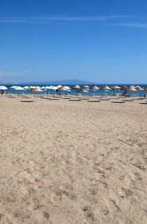 Straw parasols on the sandy beach on the Aegean Sea