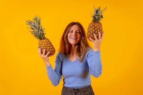 Vegetarian woman smiling with a cut pineapple