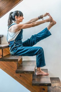 A woman doing stretching exercises on the stairs of her home. Wellbeing concept