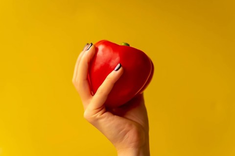 Woman's hand with a vegetable on a yellow background