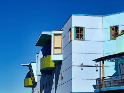 Light blue facade with colourful windows and balconies