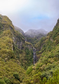 Cascata do Risco waterfall between densely forested mountains