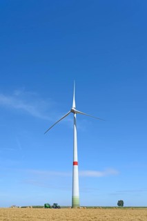Wind turbine at a stubble field with round bales of straw