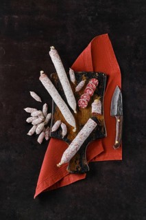 Vertical composition with fermented salami sausages on wooden cutting board