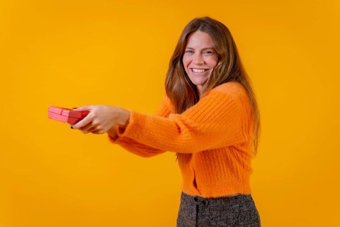 A woman delivering a gift as a surprise on a yellow background