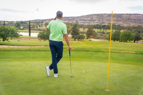 Young businessman playing golf and answering a work call with the phone